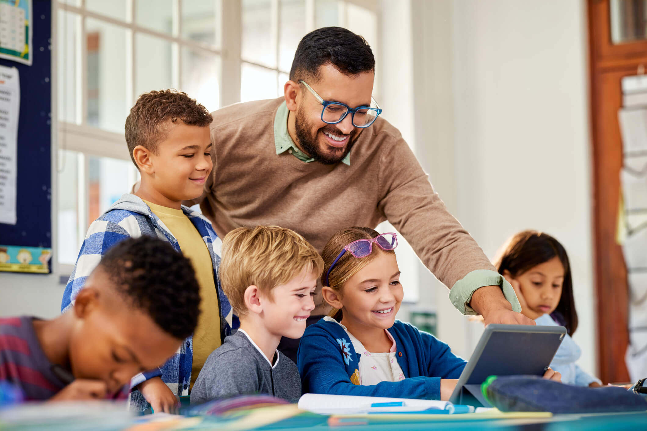 Teacher helping students with a tablet.