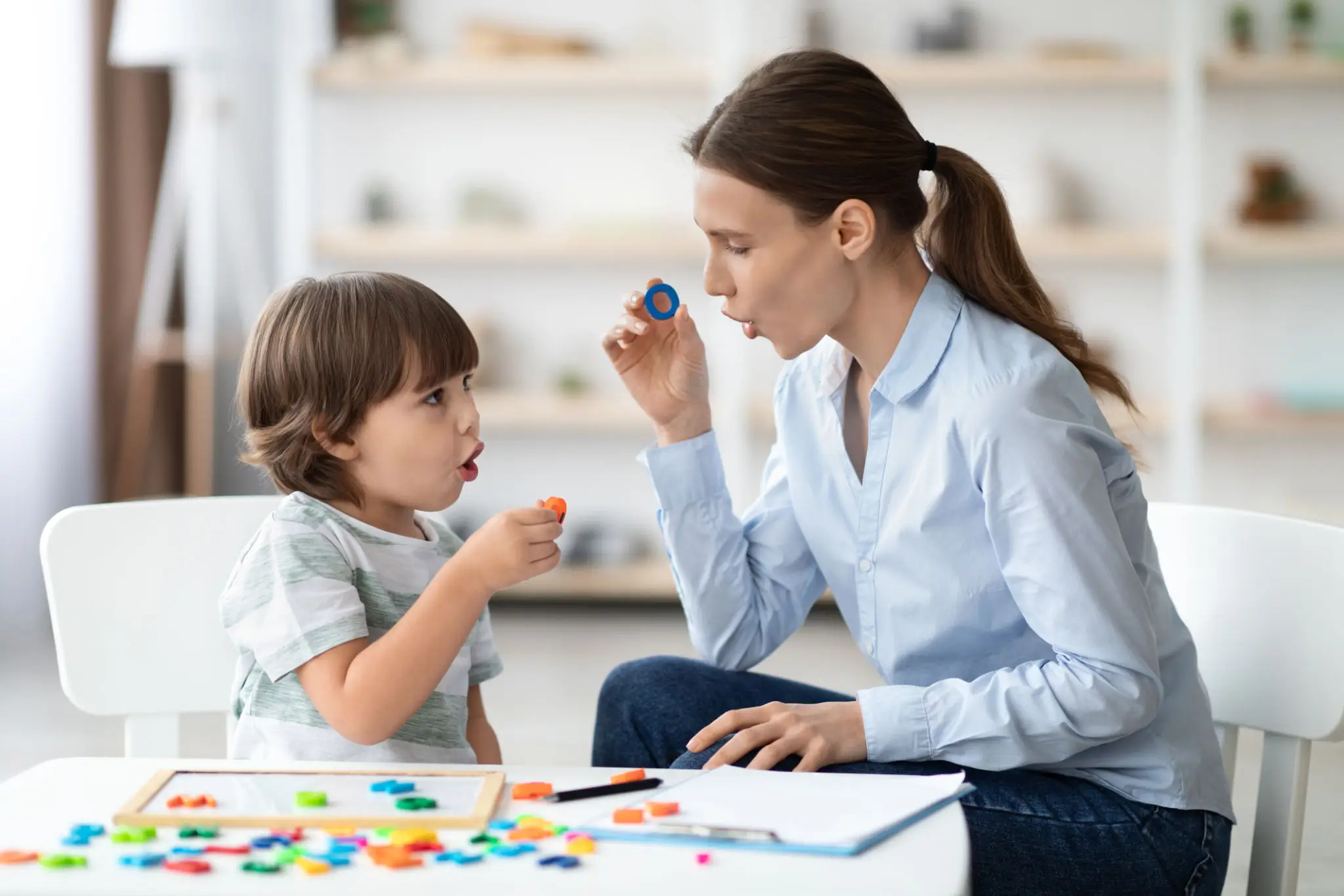 A mother and child playing a board game with colorful pieces.