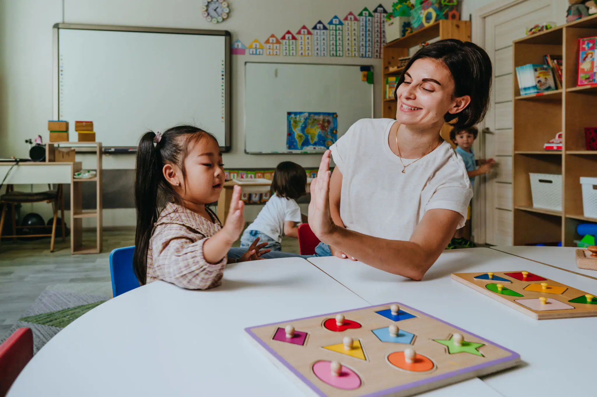 Teacher engaging a young girl in a classroom activity.
